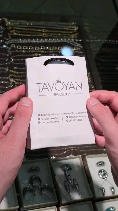 Hands holding a white Tavoyan gift bag